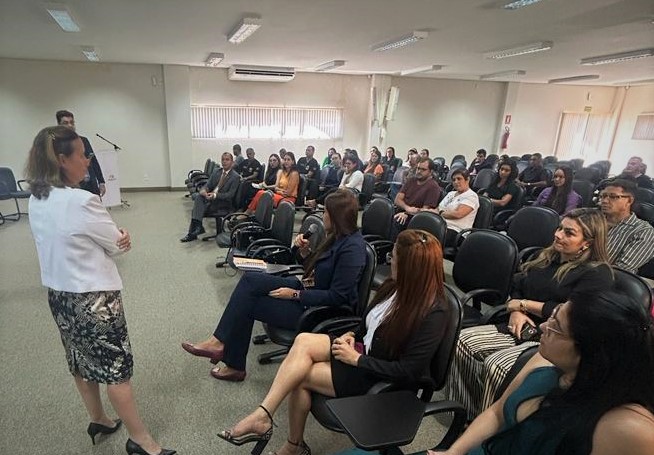 Salão com pessoas sentadas em uma reunião