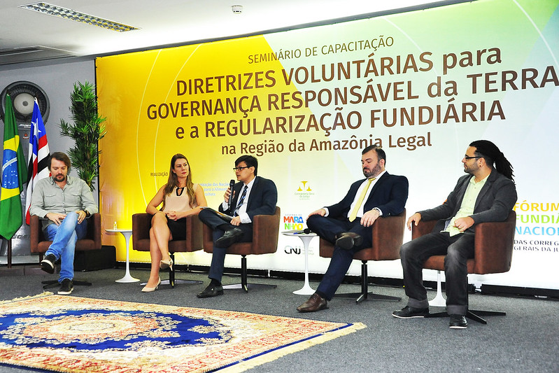Pessoas em suas cadeiras em frente a cartaz