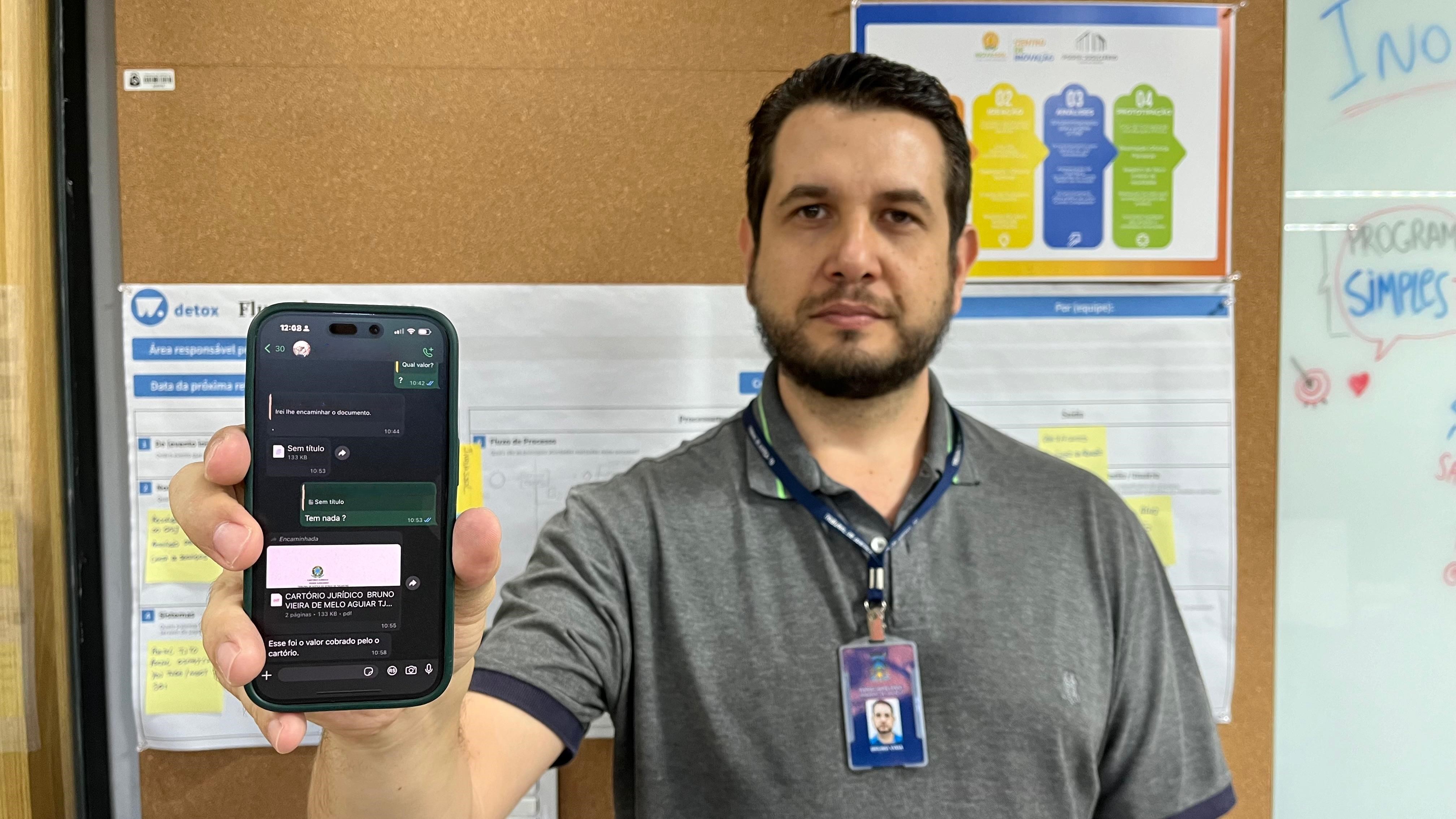 homem posa para fotografia exibindo a tela do seu celular que mostra uma tentativa de golpe via whatsapp